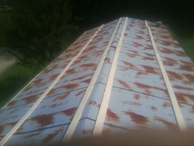 Rusted metal roof panels with new wood purlins before replacement — Storm Damage Roof Repair in Orchard by Roofing Brothers