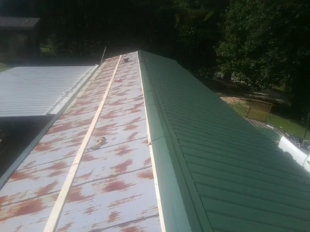 Old rusted panels beside newly installed green metal roofing — Wind Damage Roof Repair by Roofing Brothers in Orchard