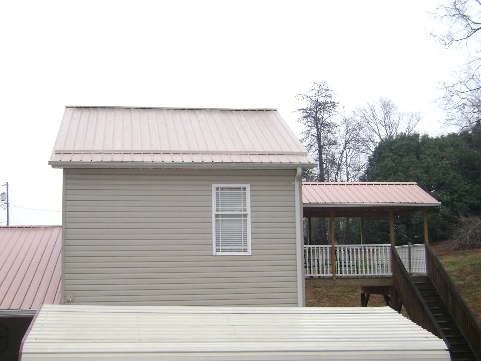 Tan metal roofs on a two story addition and attached porch, from a Roof Replacement job in Orchard