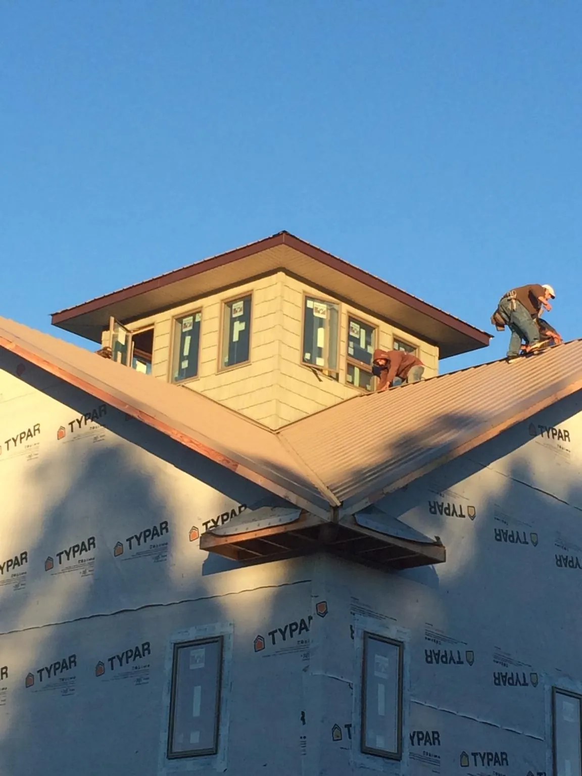 Roofers working around a rooftop cupola on a new metal roof at sunset — Roof Waterproofing in Orchard by Roofing Brothers
